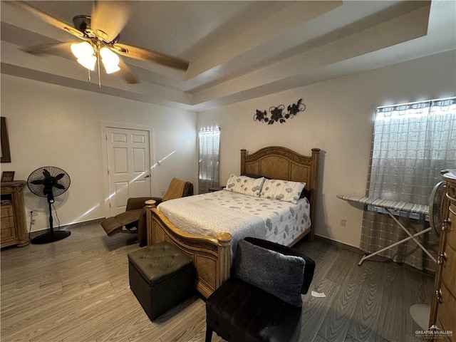 bedroom featuring a raised ceiling, ceiling fan, and light hardwood / wood-style floors