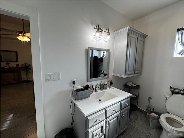 bathroom with hardwood / wood-style floors, vanity, toilet, and ceiling fan