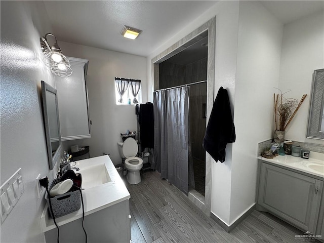 bathroom featuring a shower with shower curtain, hardwood / wood-style floors, vanity, and toilet