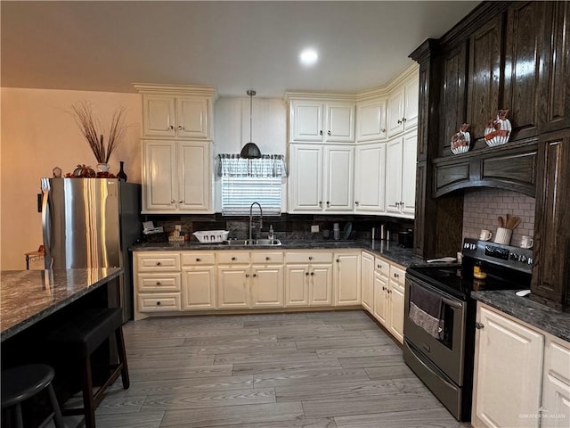 kitchen featuring decorative backsplash, dark stone countertops, black range with electric stovetop, and sink