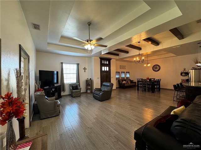 living room with wood-type flooring, ceiling fan with notable chandelier, a tray ceiling, and beam ceiling