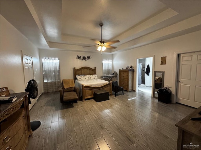 bedroom featuring hardwood / wood-style floors, ceiling fan, and a raised ceiling