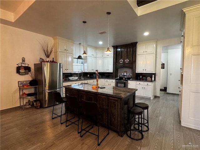 kitchen featuring a breakfast bar, appliances with stainless steel finishes, a center island, and wood-type flooring