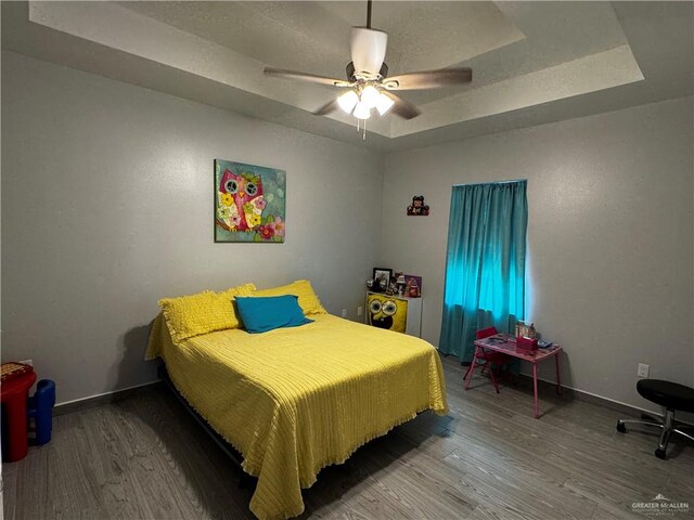 bedroom featuring a tray ceiling, ceiling fan, and hardwood / wood-style flooring