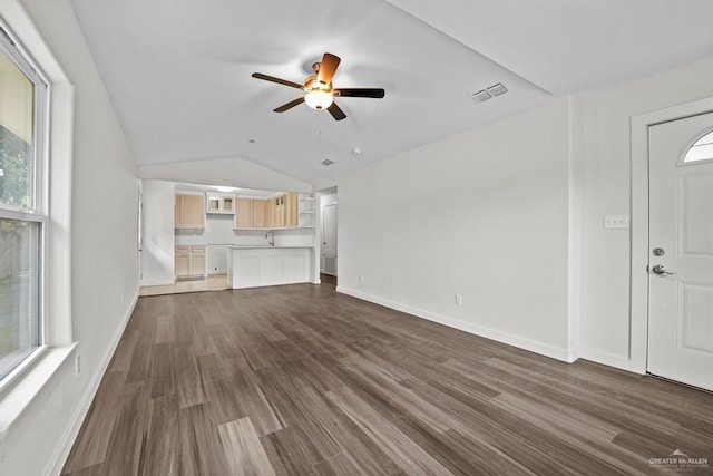 unfurnished living room with vaulted ceiling, a ceiling fan, dark wood finished floors, baseboards, and visible vents