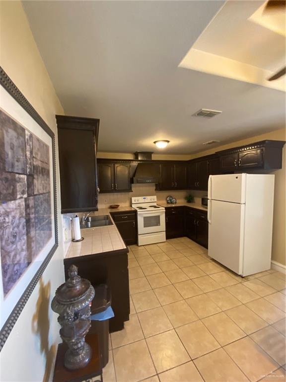 1903 E Llano Grande St, Weslaco, TX 78596 - kitchen featuring white appliances, a sink, light tile patterned floors, and tile counters