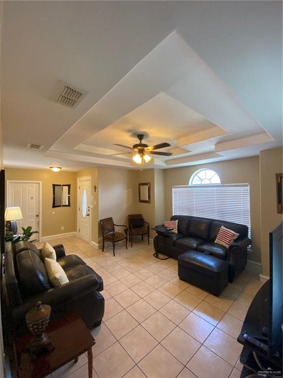 1903 E Llano Grande St, Weslaco, TX 78596 - living area with a tray ceiling, light tile patterned flooring, baseboards, and ceiling fan
