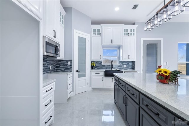 kitchen with plenty of natural light, sink, white cabinets, and decorative light fixtures