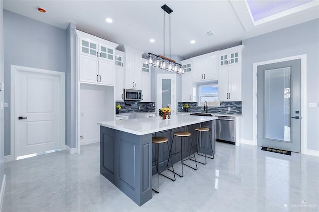 kitchen with white cabinetry, decorative light fixtures, stainless steel appliances, and a center island