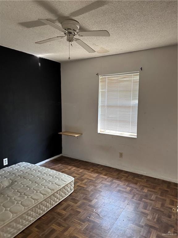 spare room with dark parquet flooring, a textured ceiling, and ceiling fan