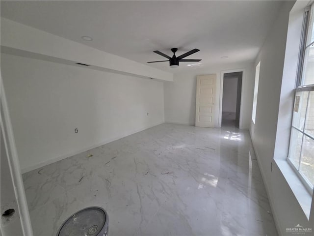 empty room featuring baseboards, visible vents, a ceiling fan, and marble finish floor