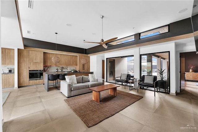 living room featuring ceiling fan, a towering ceiling, and light tile patterned flooring