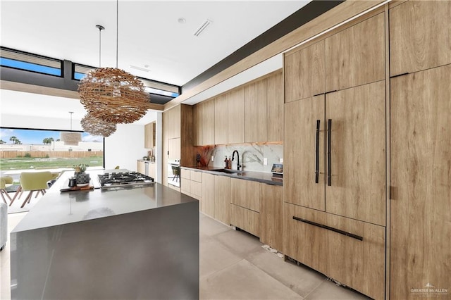 kitchen featuring sink, tasteful backsplash, a center island, pendant lighting, and stainless steel gas stovetop