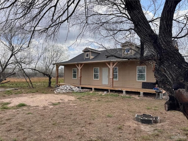 view of front of house with an outdoor fire pit and a shingled roof