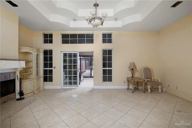 interior space featuring light tile patterned floors, a tray ceiling, a premium fireplace, and a high ceiling