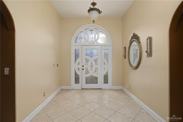 entrance foyer featuring arched walkways, baseboards, and light tile patterned floors