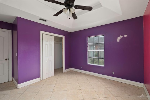 unfurnished bedroom with a tray ceiling, visible vents, and baseboards