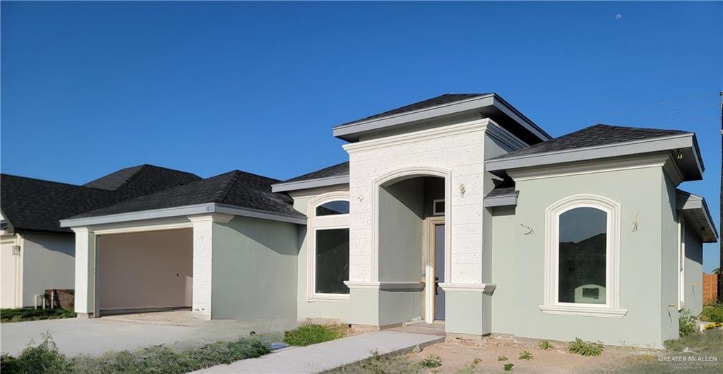 view of front of house featuring a garage, stucco siding, and a shingled roof