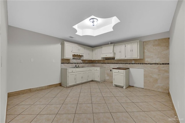 1619 Beech Ave, Mercedes, TX 78570 - kitchen with custom exhaust hood, light tile patterned floors, white cabinetry, a sink, and baseboards