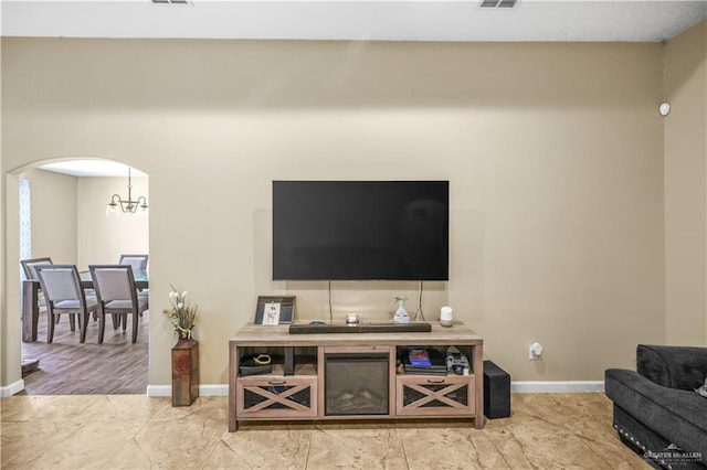 living room with arched walkways, a chandelier, visible vents, and baseboards