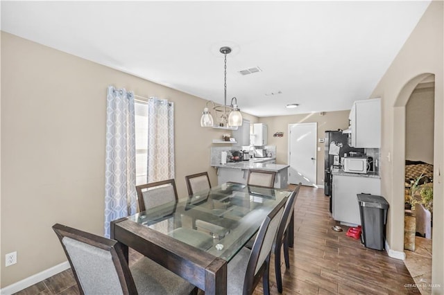 dining room with visible vents, arched walkways, baseboards, and dark wood-style floors