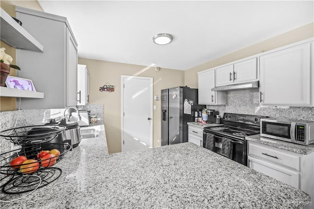 kitchen featuring under cabinet range hood, light stone counters, decorative backsplash, appliances with stainless steel finishes, and open shelves