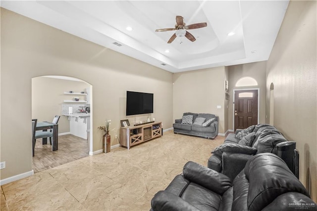 living room with arched walkways, baseboards, and a ceiling fan