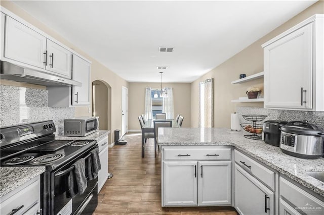 kitchen with visible vents, black electric range oven, under cabinet range hood, stainless steel microwave, and arched walkways