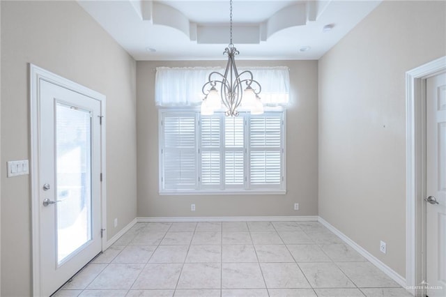 unfurnished dining area with a notable chandelier, light tile patterned flooring, a raised ceiling, and a wealth of natural light