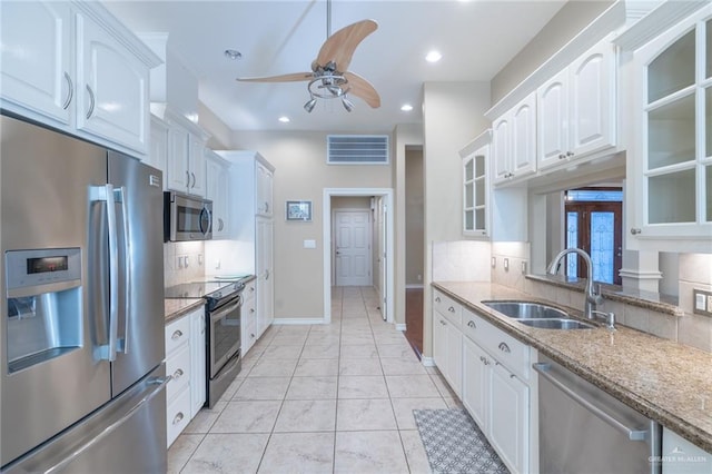 kitchen featuring white cabinetry, sink, ceiling fan, stainless steel appliances, and light stone counters