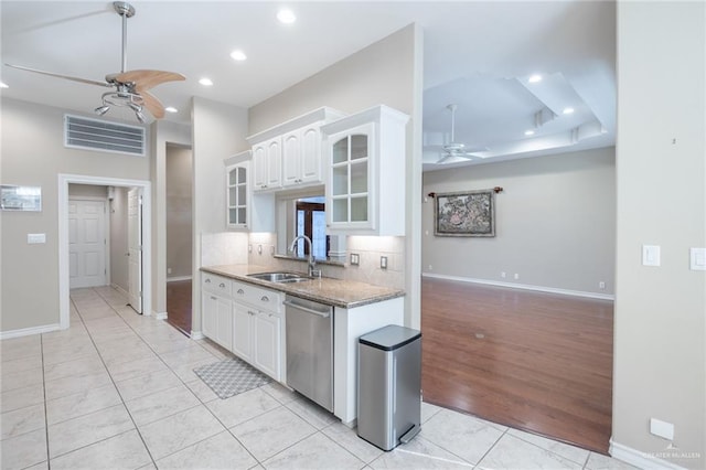 kitchen with light stone countertops, light wood-type flooring, stainless steel dishwasher, sink, and white cabinetry