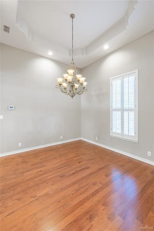 spare room featuring hardwood / wood-style floors and a notable chandelier