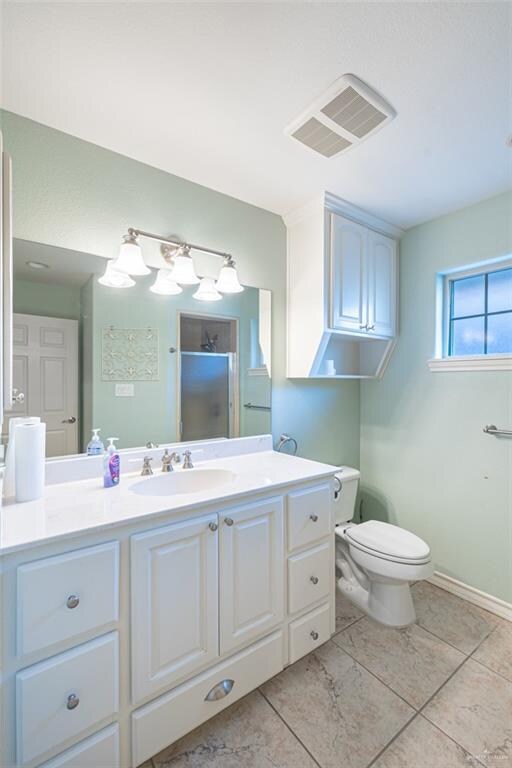 bathroom with tile patterned floors, vanity, toilet, and a shower with door