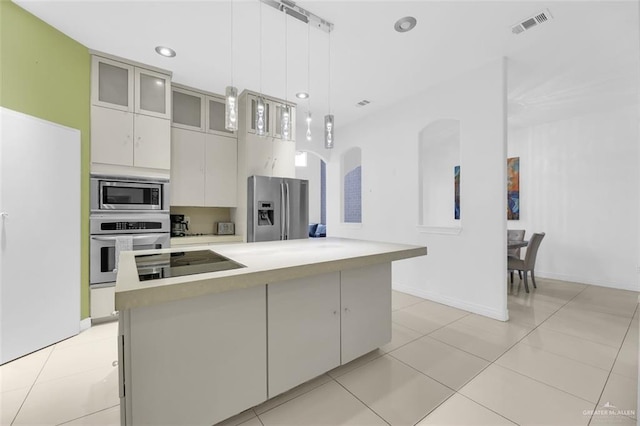 kitchen with stainless steel appliances, pendant lighting, light tile patterned floors, white cabinets, and a kitchen island