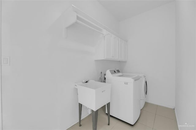 washroom with separate washer and dryer, light tile patterned flooring, and cabinets