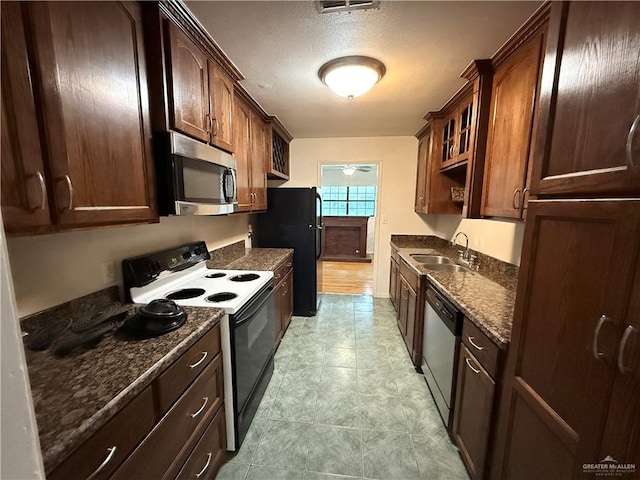 kitchen with sink, dark stone counters, a textured ceiling, and appliances with stainless steel finishes