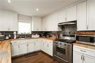 kitchen featuring dark hardwood / wood-style flooring, white cabinetry, appliances with stainless steel finishes, and tasteful backsplash