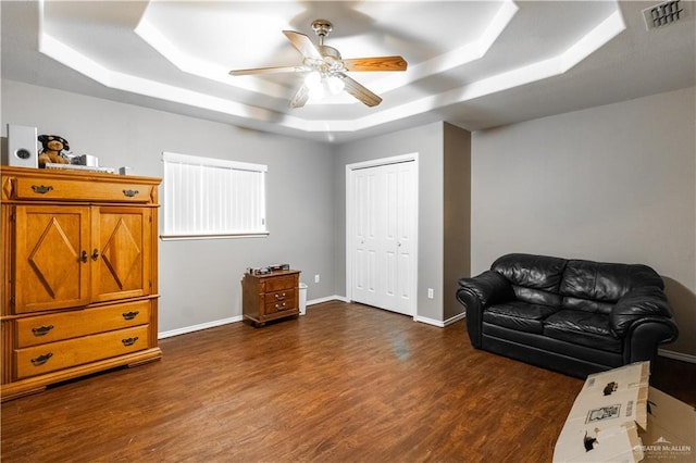 living area featuring a tray ceiling, ceiling fan, and dark hardwood / wood-style floors