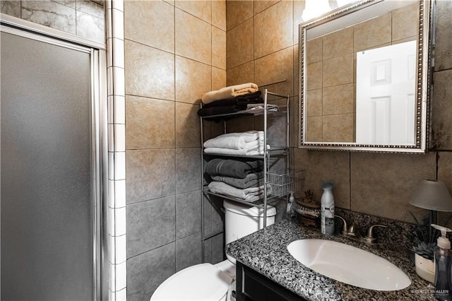 bathroom with tile walls, vanity, an enclosed shower, and toilet