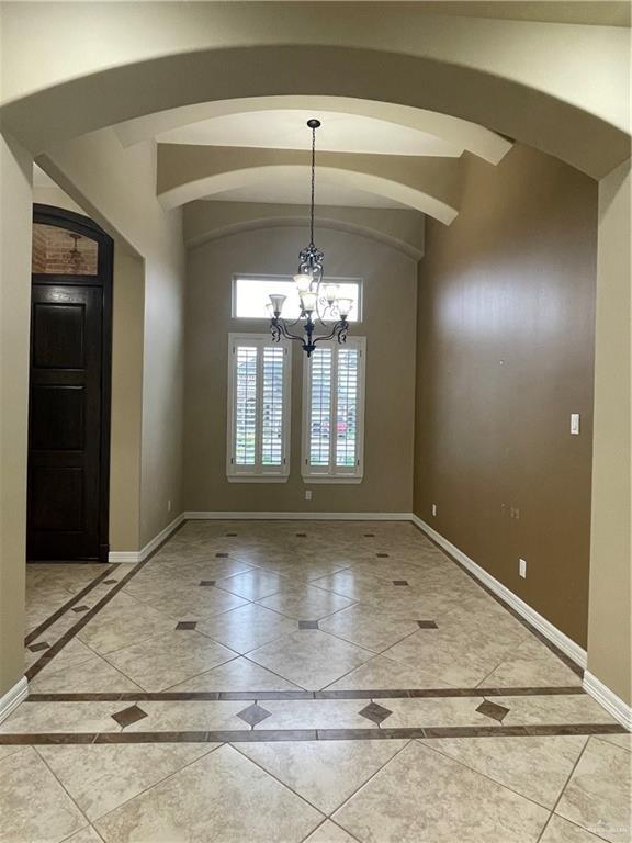 10210 N 28th Ln, Mcallen, TX 78504 - unfurnished dining area with inlaid floor details, arched walkways, and a chandelier