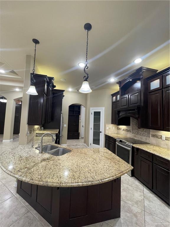 10210 N 28th Ln, Mcallen, TX 78504 - kitchen with stainless steel range with electric cooktop, decorative backsplash, glass insert cabinets, a peninsula, and recessed lighting