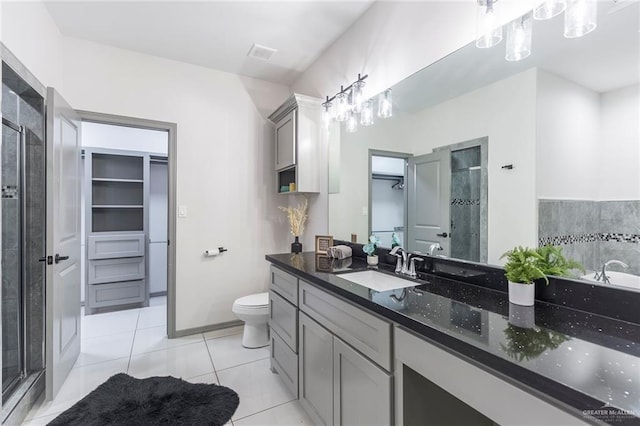 bathroom featuring toilet, a shower with door, vanity, and tile patterned flooring