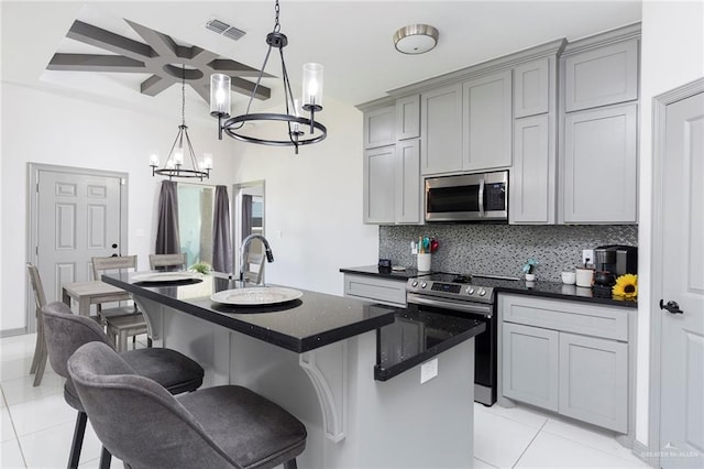 kitchen with gray cabinets, light tile patterned floors, stainless steel appliances, and a kitchen island with sink