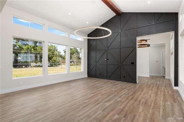 17956 Garrett Rd, Harlingen, TX 78552 - unfurnished living room featuring light wood-style floors, beamed ceiling, an accent wall, a decorative wall, and high vaulted ceiling