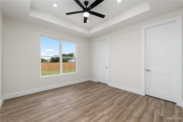 17956 Garrett Rd, Harlingen, TX 78552 - unfurnished bedroom featuring a raised ceiling, light wood-style floors, recessed lighting, and ceiling fan