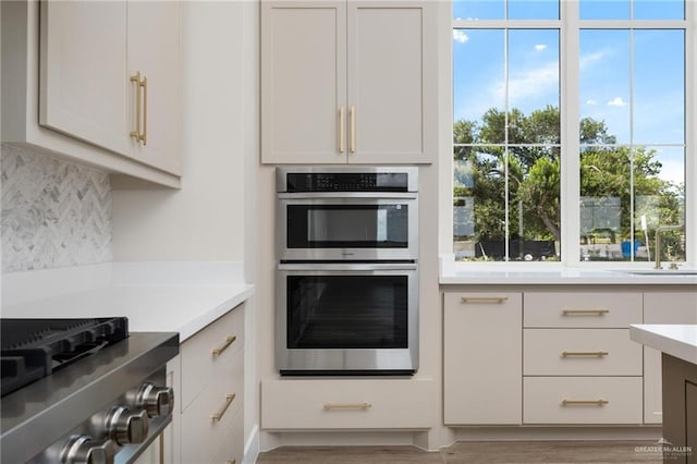 17956 Garrett Rd, Harlingen, TX 78552 - kitchen with stainless steel appliances, backsplash, light countertops, wood finished floors, and white cabinetry