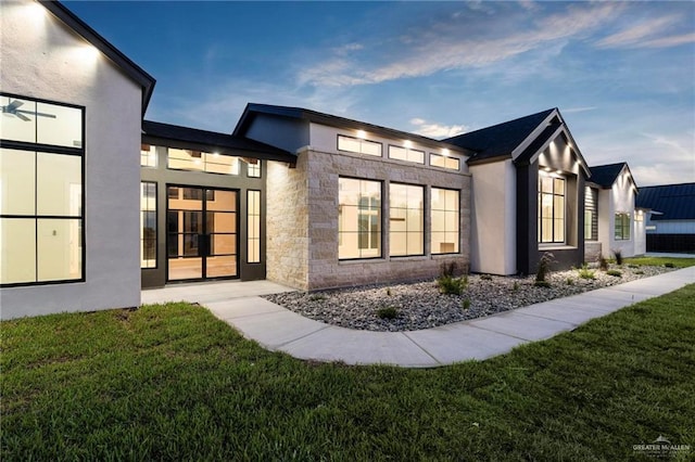 17956 Garrett Rd, Harlingen, TX 78552 - rear view of house with stone siding, a yard, and stucco siding