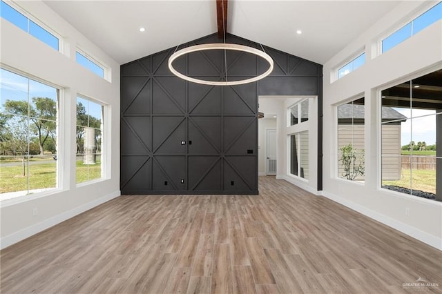 17956 Garrett Rd, Harlingen, TX 78552 - unfurnished living room with beamed ceiling, wood finished floors, high vaulted ceiling, and an accent wall