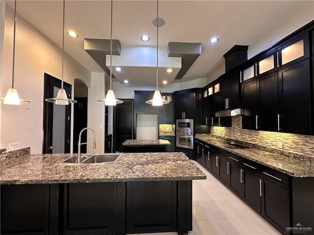 kitchen with decorative backsplash, light stone countertops, stainless steel appliances, sink, and hanging light fixtures