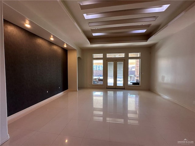 tiled spare room with french doors and a raised ceiling